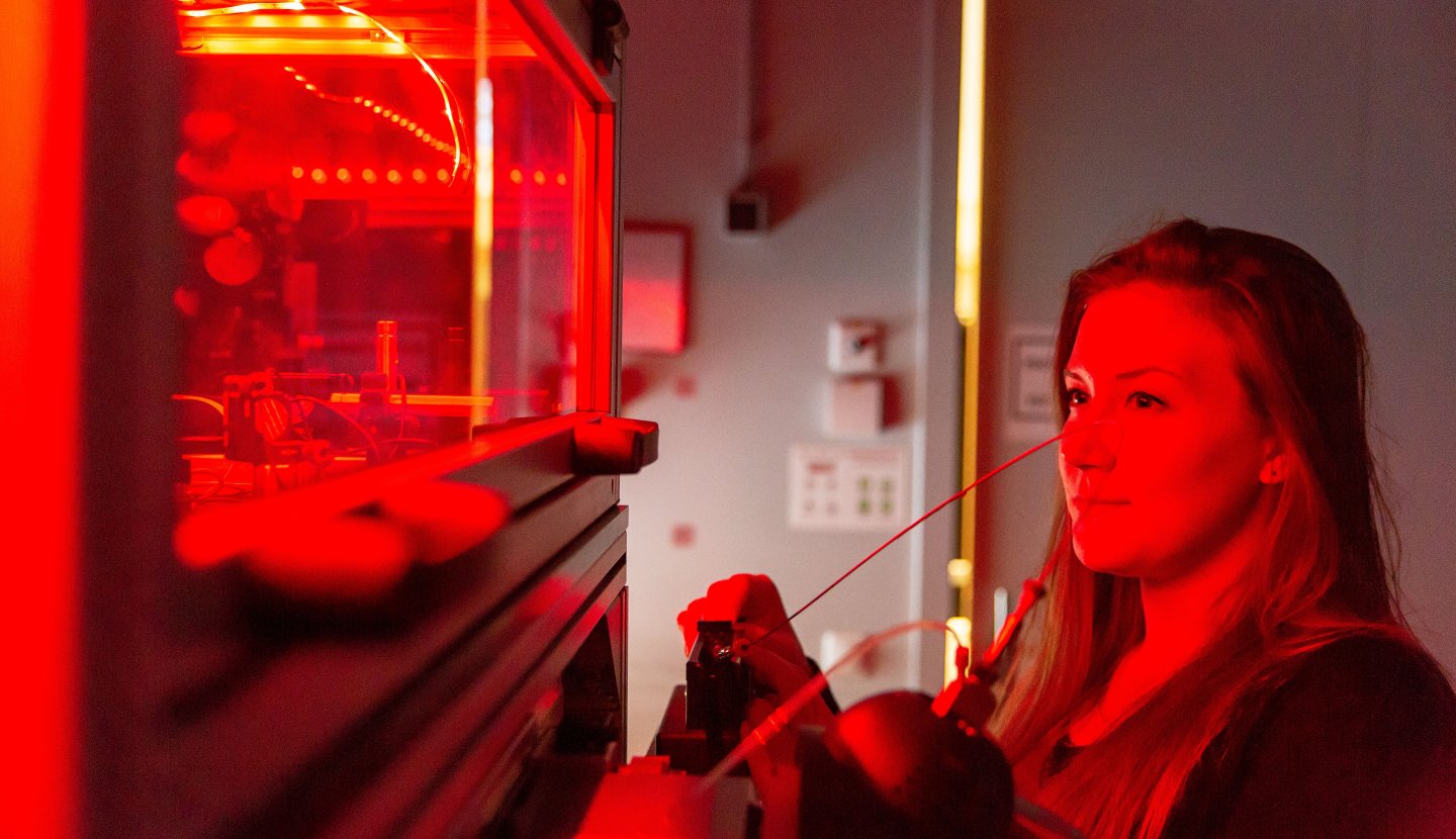 Vrouw in een lab kijkt naar glas met rood licht