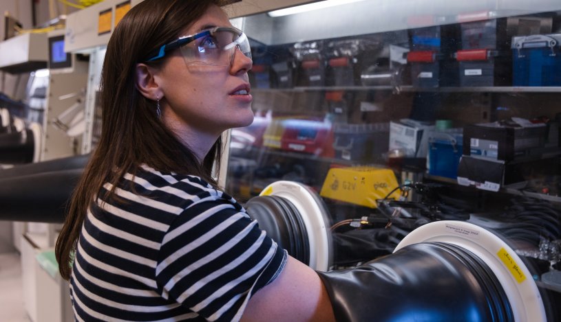 Medewerker van AMOLF werkt in een laboratorium met een apparaat met een handschoenenkast