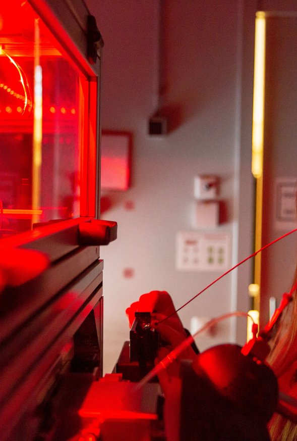 Vrouw in een lab kijkt naar glas met rood licht