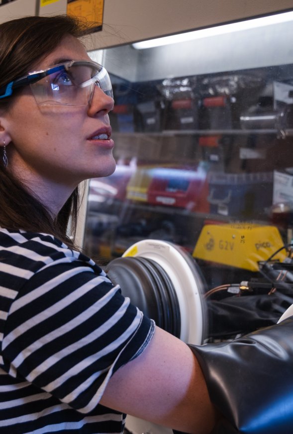 Medewerker van AMOLF werkt in een laboratorium met een apparaat met een handschoenenkast
